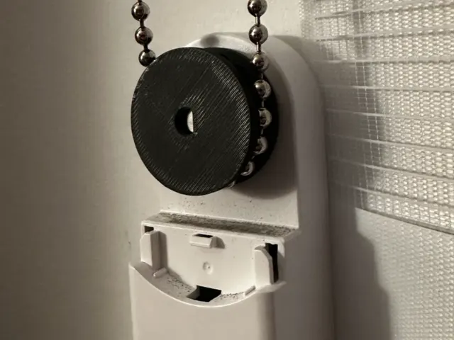 A black printed gear on a roller blind, turned by a metal ball chain