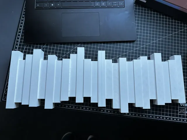 A white coat rack of upright slats at uneven heights, laid flat on a cutting mat